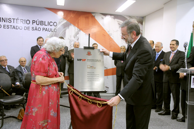 duas pessoas tirando o pano da placa do memorial mpsp